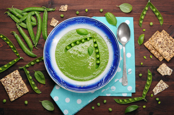 Light dietary cream soup from vegetables (potatoes, carrots, spinach and green peas) on a dark wooden surface. Low-calorie product for weight loss. Vegetarian, vegan concept. Organic food