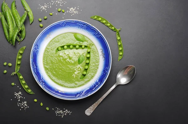 Light dietary cream soup from vegetables (potatoes, carrots, spinach and green peas) on a dark surface. Low-calorie product for weight loss. Vegetarian, vegan concept. Organic food