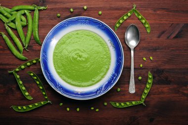 Diyet çorbası ile bir tabak kahverengi ahşap tahta üzerinde mavi bir sınır ile yeşil bezelye püresi. Diyet düşük kalorili ev yemekleri. Vejetaryen, vegan kavramı