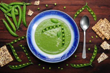 Diyet çorbası ile bir tabak kahverengi ahşap tahta üzerinde mavi bir sınır ile yeşil bezelye püresi. Diyet düşük kalorili ev yemekleri. Vejetaryen, vegan kavramı