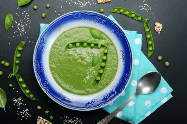 Diyet çorbası ile bir kara tahta üzerinde mavi kenarlıklı bir tabak içinde yeşil bezelye püresi. Diyet düşük kalorili ev yemekleri. Vejetaryen, vegan kavramı