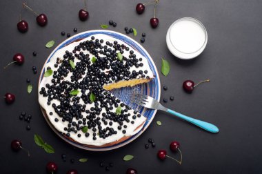 Kek (bisküvi) krem ve karanlık bir arka plan üzerinde mavi bir plaka üzerinde yaban mersini. Hafif yaz ev kek