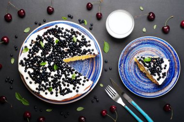 Kek (bisküvi) krem ve karanlık bir arka plan üzerinde mavi bir plaka üzerinde yaban mersini. Hafif yaz ev kek