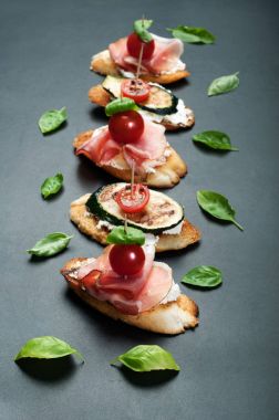 Krem peynir, jambon, kiraz domates, fesleğen yaprağı, kabak ve ızgara patlıcan ile tost. Lezzetli taze pişmiş snack (sandviç ev yapımı)