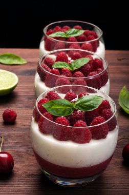 Ahududulu jöle, krem sos ve koyu ahşap yüzeye bardaklarda olgun ahududu hafif yaz tatlı yaptı. Lezzetli tatlı ev yapımı tatlı yemek