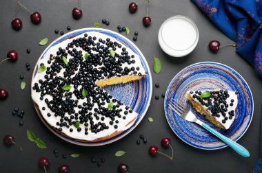 Bir sünger kek krem ve yaban mersini, karanlık bir tahta üzerinde mavi bir tabakta kaplı. İkinci plaka yanında, üzerinde hangi yalan bir parça kek ve bir bardak süt. Lezzetli ev yapımı tatlılar