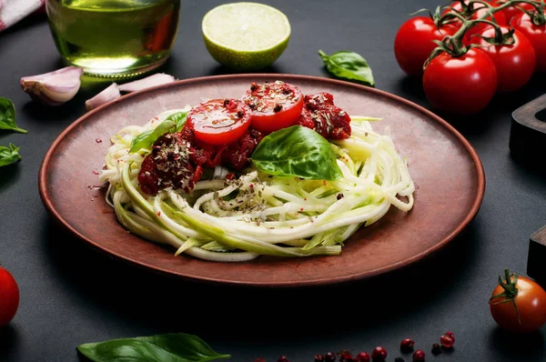 İlave vegan yapıştırın genç kabak ve domates sosu ile baharat kahverengi kil tabakta. Diyet düşük kalorili yemek ev yapımı.