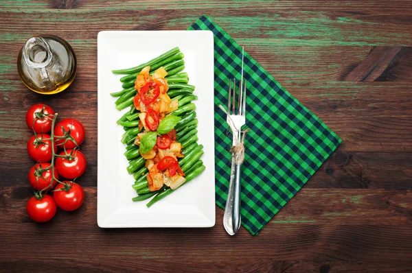 Spargelbohnen mit Paprika und Tomatensauce auf einem weißen rechteckigen Teller passieren. Kalorienarmes veganes Gericht — Stockfoto