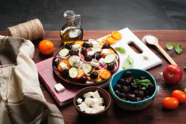 Akdeniz mutfağı. Domates, salatalık, mor soğan ve karanlık bir arka plan üzerinde kahverengi bir tabakta Sele zeytin salata. Füzyon Yunan salatası. Lezzetli ve sağlıklı mevsimlik yemek.
