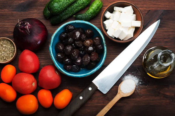 Productos de la cocina mediterránea. Aceite de oliva, aceitunas secas al sol, feta, tomates y hojas de albahaca en una tabla de madera marrón . —  Fotos de Stock