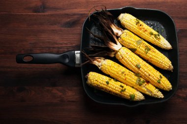 Mısır, zeytinyağı, biber, fesleğen ve tuz bir tavada kızarmış. Koyu ahşap yüzey.