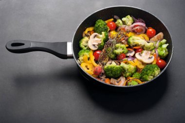 Frying pan with fried vegetables on a dark surface. Low-calorie dietary summer menu. Vegetarian, vegan concept clipart