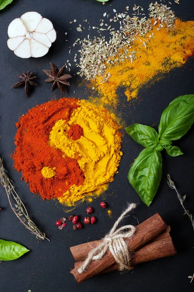 Paprika and turmeric in the form of a figure of "yin yang" on a dark surface. Spices, condiments, herbs on a dark surface — Stock Photo, Image