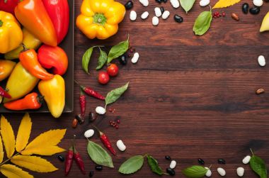 Sonbahar arka plan. Sulu kırmızı biber, domates ve fesleğen yaprakları kahverengi ahşap yüzeyde. Organik ürünler. Metin için yer