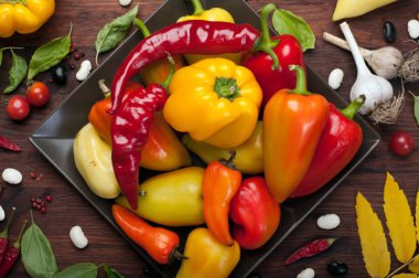 Bir kare plaka üzerinde farklı çeşitlerinin sarı ve kırmızı biber. Çiğ sebze. Hasat gıda