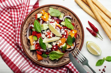 Salata çanak yapılmış domates, biber, salatalık, mor soğan, fesleğen yaprağı, süzme peynir, zeytinyağı ve limon suyu beyaz zemin üzerinde. Yararlı bir yemek. Sağlıklı beslenme, dengeli beslenme