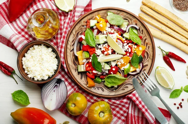 Salad dish made of tomatoes, peppers, cucumbers, purple onions, basil leaves, cottage cheese, olive oil and lime juice on a white background. A useful dish. Healthy eating, balanced nutrition — Stock Photo, Image