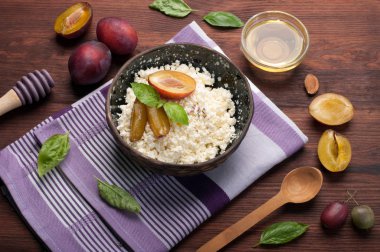 Kahvaltı kavramı. Süzme peynir ve Erik bir koyu ahşap yüzeyde bir seramik tabak içinde. Dengeli beslenme. Organik ürünler