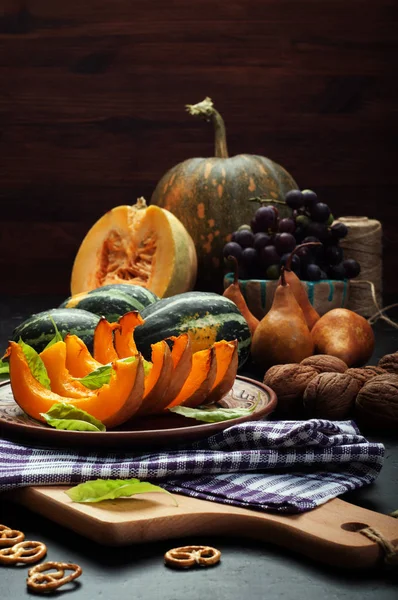 秋天的季节性产品。在褐色粘土板的烤的南瓜。附近的葡萄、 多彩南瓜、 梨、 核桃、 石楠花。素食主义者，素食菜单。模糊的背景，选择性的锐度 — 图库照片