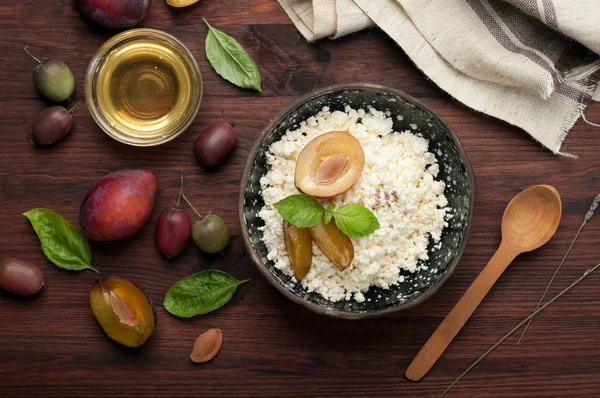 Concepto de desayuno. Queso de cabaña y ciruela en un plato de cerámica sobre una superficie de madera oscura. Dieta equilibrada. Productos ecológicos —  Fotos de Stock