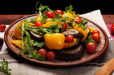 Akdeniz mutfağı. Sıcak fırında biber, patlıcan, roka yaprakları ve kahverengi kil tabakta domates salatası. Vegan kavramı. Diyet düşük kalorili yemek