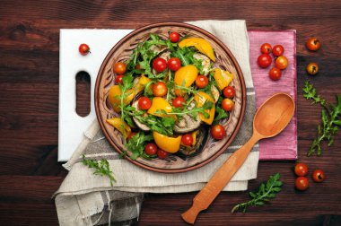 Akdeniz mutfağı. Sıcak fırında biber, patlıcan, roka yaprakları ve kahverengi kil tabakta domates salatası. Vegan kavramı. Diyet düşük kalorili yemek