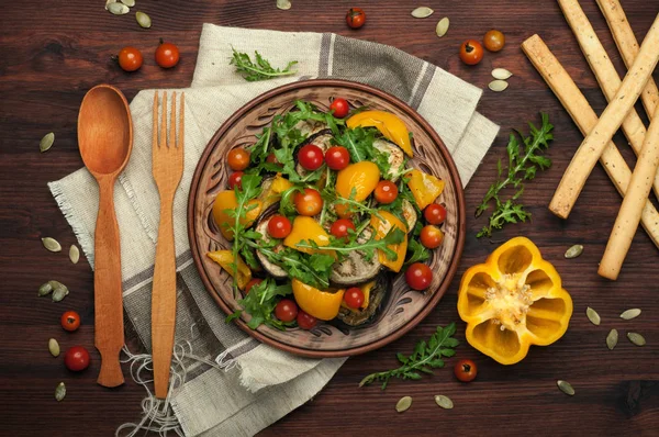 Akdeniz mutfağı. Sıcak fırında biber, patlıcan, roka yaprakları ve kahverengi kil tabakta domates salatası. Vegan kavramı. Diyet düşük kalorili yemek — Stok fotoğraf