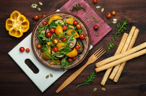 地中海美食。温暖的沙拉菜烤的辣椒、 茄子、 芝麻菜叶子和樱桃番茄的褐色粘土板上。素食主义者的概念。膳食低热量食品 — 图库照片