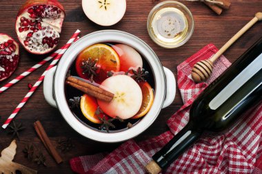 Dilim elma, portakal, tarçın, karanfil ve anason kahverengi ahşap arka plan üzerinde mulled şarap. Tatlım, bir şişe şarap ve yarım bir nar yanında. Lezzetli ısınma kış içecek.