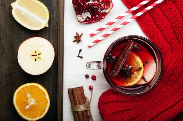 Coupe en verre avec vin chaud, avec des tranches de pomme, orange, épices et miel sur un fond de bois blanc. Près de l'écharpe rouge, tranches de pomme, orange et citron. Boisson de Noël et Nouvel An d'hiver — Photo