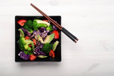 Brokoli, mor lahana, domates ve tatlı sosu ve zeytinyağı Beyaz ahşap zemin üzerinde siyah bir kare plaka ile Avokado salatası. Sağlıklı Diyet beslenme kavramı. Metin için yer