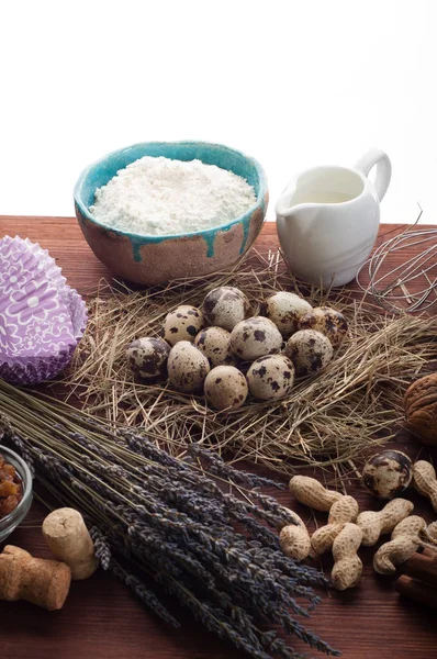 Un conjunto de productos para cocinar. Fondo culinario. Lugar para el texto. Crema, huevos de codorniz, nueces, especias y gadgets para cocinar sobre un fondo de madera marrón . — Foto de Stock