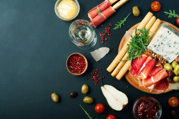 Mediterrane producten (ham, blauwe kaas, rucola, kersen, noten) op een donkere bord. Nuttige natuurlijke vers voedsel — Stockfoto