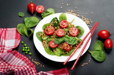 Salata bebek ıspanak yaprakları, yeşil mercimek, domates, zeytin yağı ve koyu bir yüzey üzerinde bir kapta limon suyu. Bir diyet yemek. Vejetaryen, vegan kavramı 
