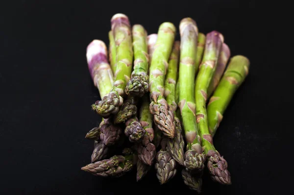 Asparagi crudi su superficie scura. Macro che spara. Profondità di campo bassa, sfondo sfocato — Foto Stock