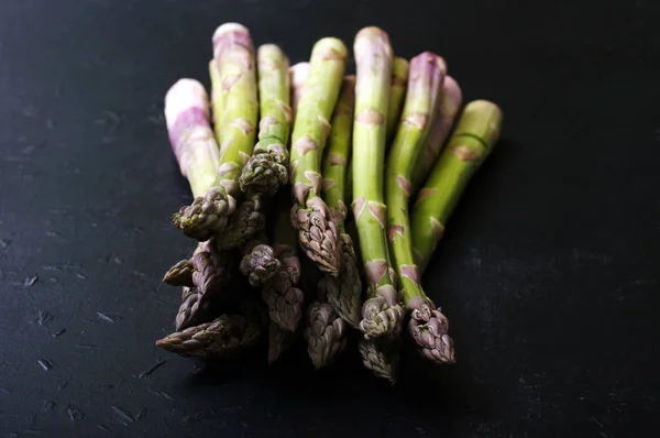 Asparagi crudi su superficie scura. Macro che spara. Profondità di campo bassa, sfondo sfocato — Foto Stock