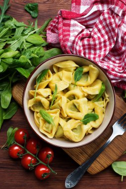 Hazır tortellini, ricotta ve ıspanaklı, siyah bir ahşap üzerinde. 
