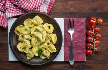 Hazır tortellini, ricotta ve ıspanaklı, siyah bir ahşap üzerinde. 