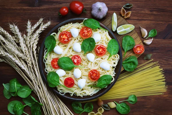 Pasta Met Kerstomaten Spinazie Mozzarella Een Bruine Kleiplaat Naast Knoflook — Stockfoto