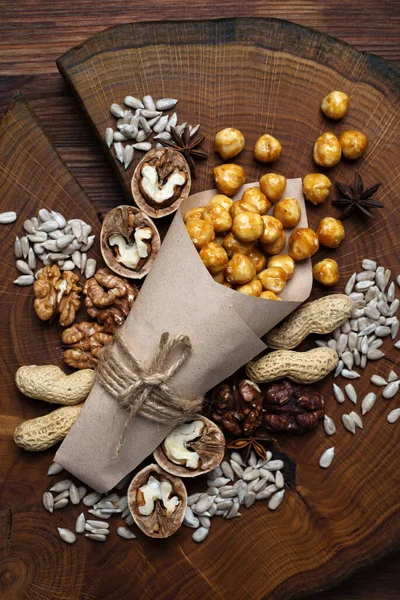茶色の木製の表面にナッツや種子の様々な 中央にキャラメルヘーゼルナッツ — ストック写真