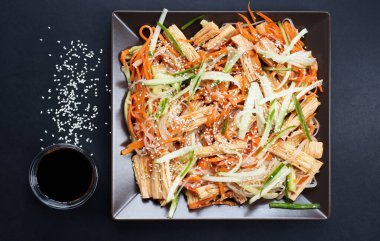 Fasulye erişteli Fuju salatası, havuç turşusu, salatalık ve koyu arkaplanda susam tohumları. Soya sosunun yanında. Asya mutfağı