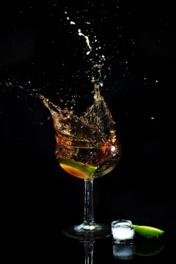 Siyah arka planda bardaktan dökülen kola ve limonlu kokteyl. Siyah arka planda iç