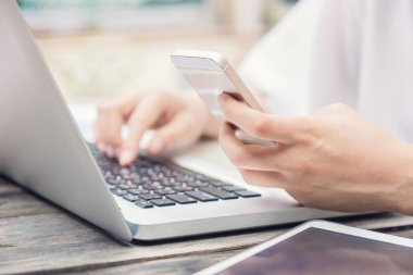 Eller üstünde laptop klavye ve akıllı telefon