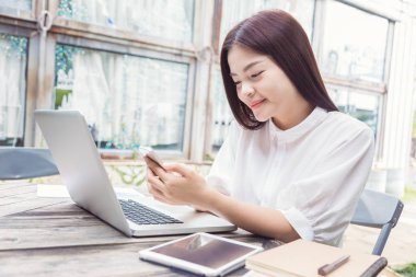 Genç mutlu rahat Asyalı kadın onun laptop co teknolojisini kullanarak