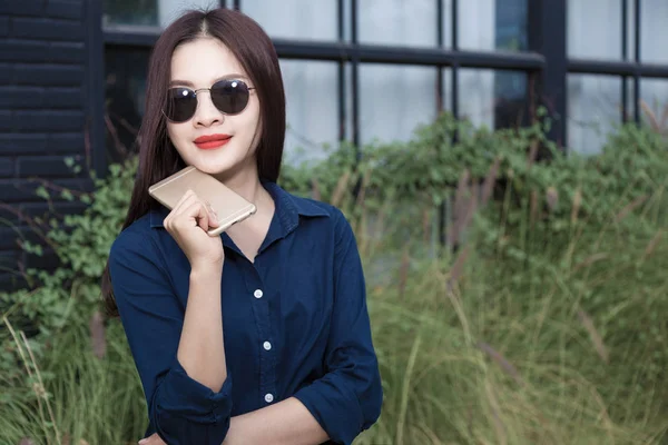 C tutarak güneş gözlüğü takmış casule giysili genç Asyalı kadın — Stok fotoğraf