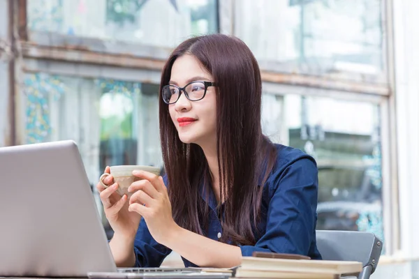 Joven asiático mujer celebración taza de café y tomando un descanso de — Foto de Stock