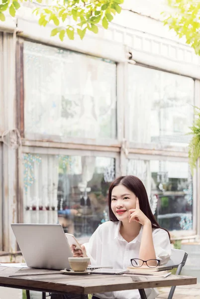 happy young asian woman thinking and enjoying her coffee while u