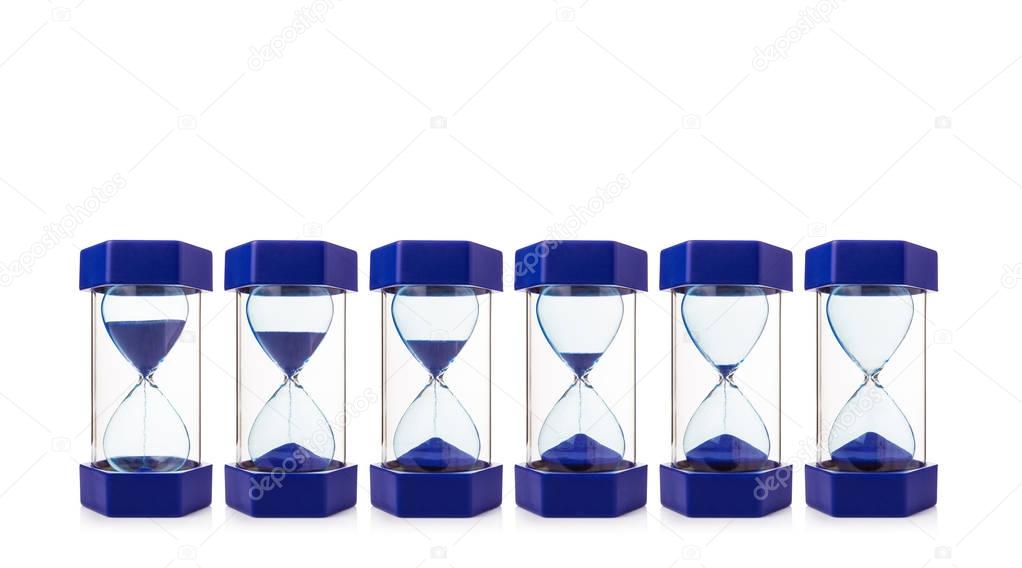 row of six hourglasses showing blue sand dropping from almost fu