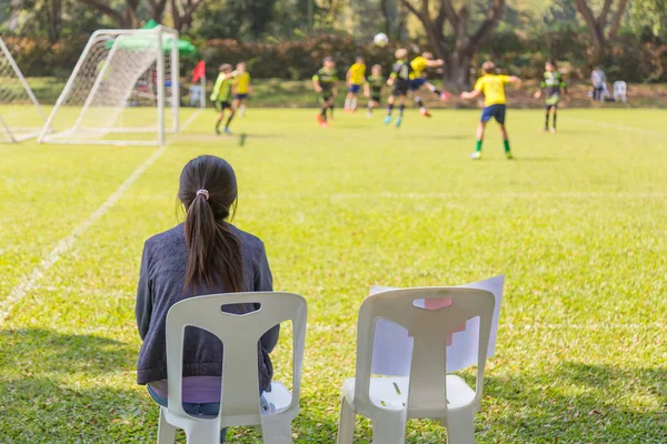 Vrouw kijken naar een voetbalwedstrijd van school jongen op een zonnige dag — Stockfoto