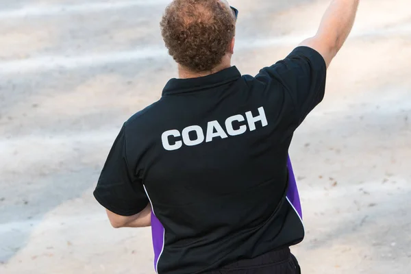 back of a coach's black color shirt with the word Coach written